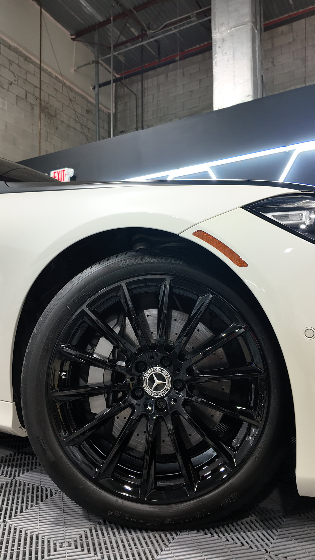 Close-up of a white car with black alloy wheels in an indoor setting