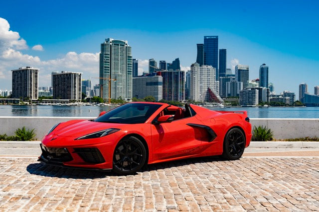 Red sports car on a brick road with a city skyline in the background