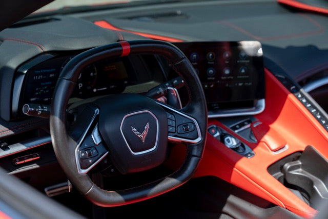 Car interior with steering wheel and dashboard featuring a logo.