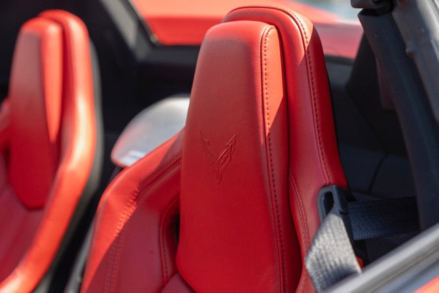 Close-up of red car seats with a visible logo, likely from a luxury vehicle brand.
