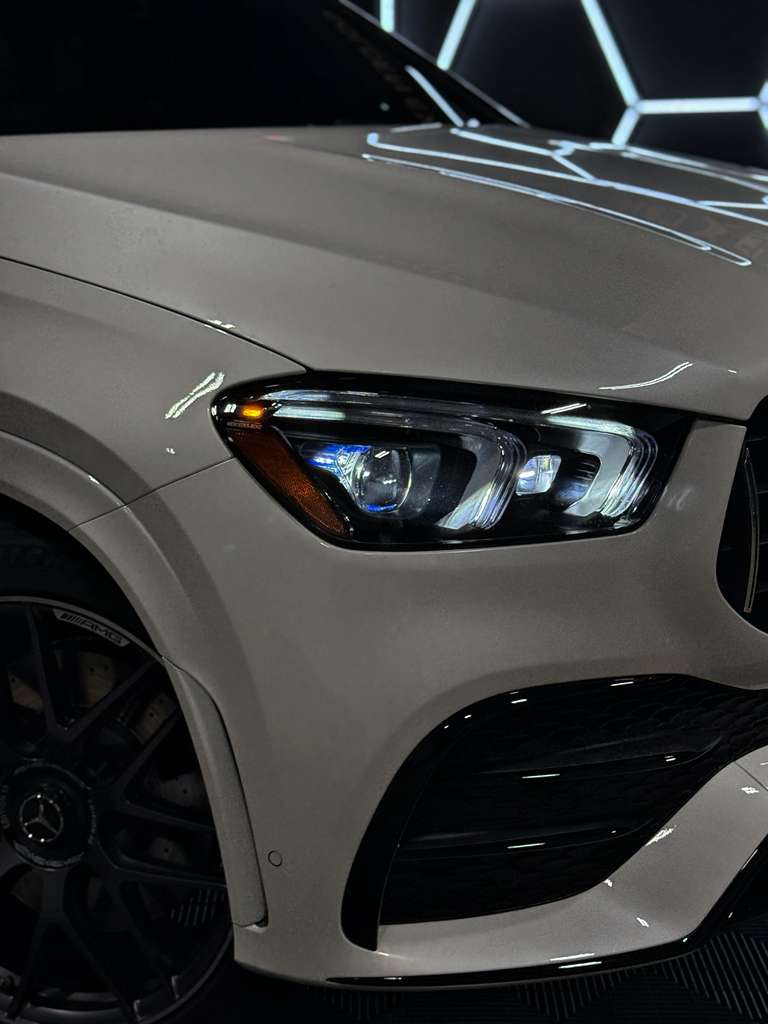 Close-up of a car's headlight and front grille on a dark background