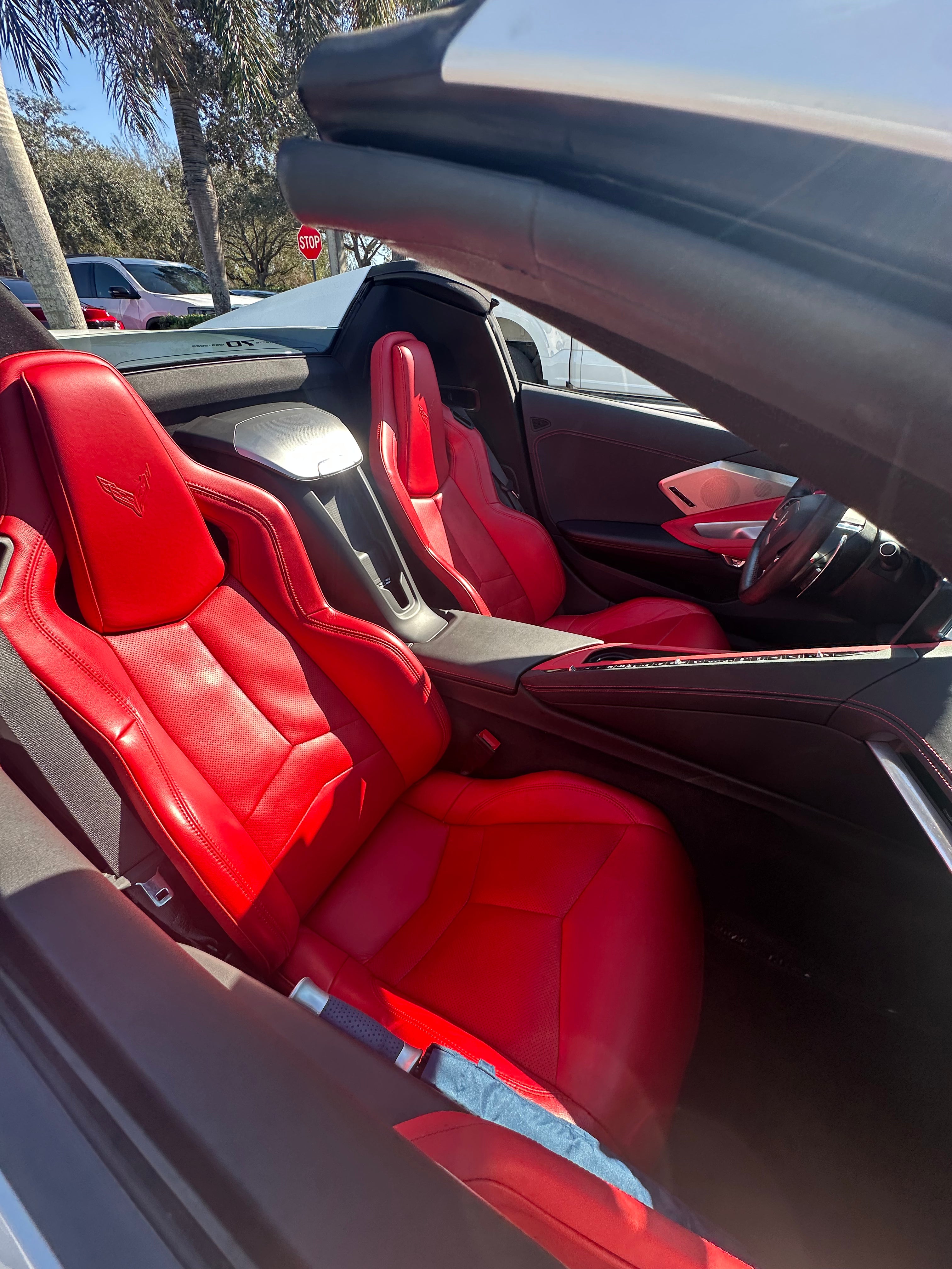 Red car interior with open door showing dashboard and steering wheel.