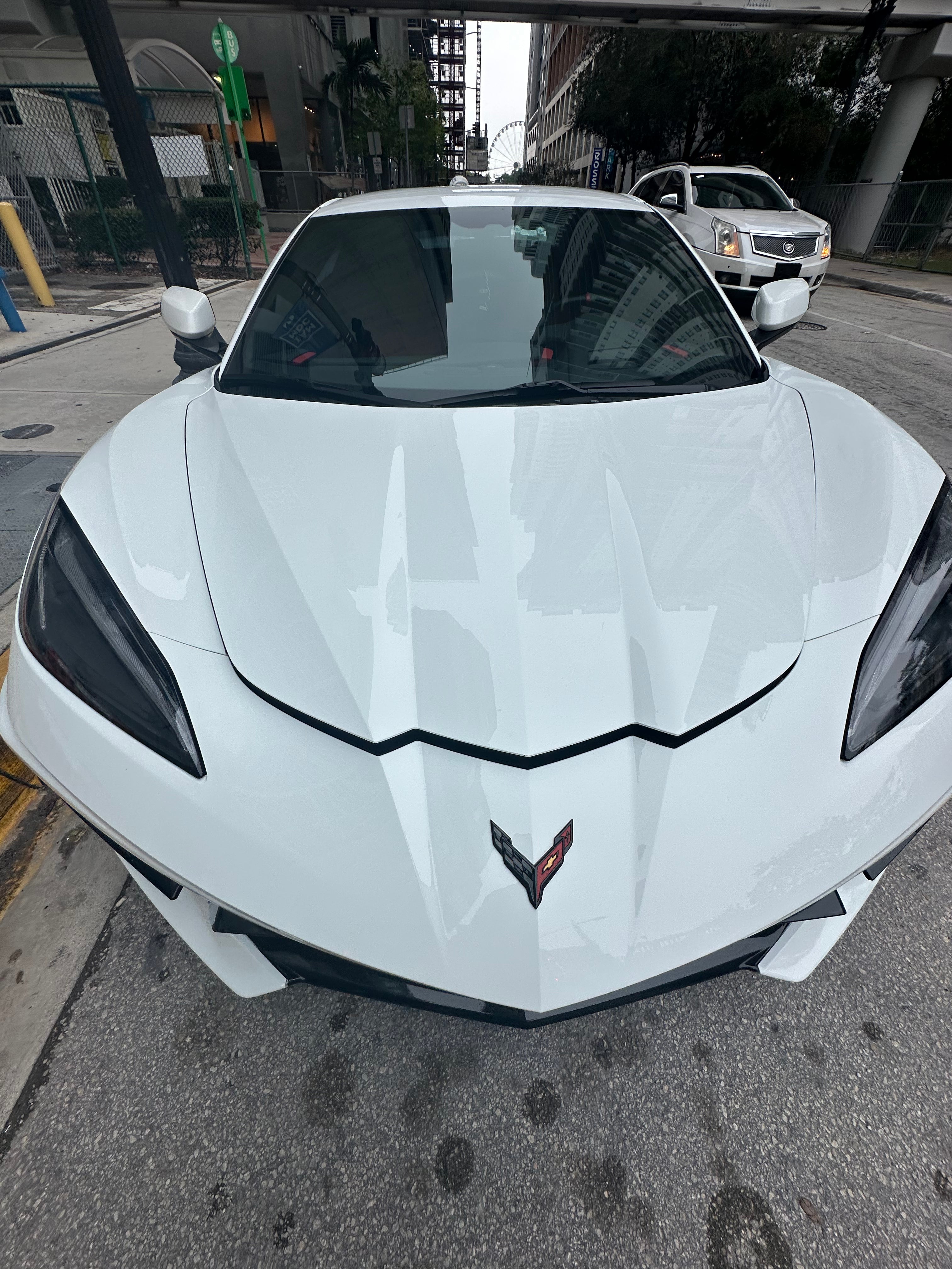 White sports car with a visible Chevrolet logo on a city street.