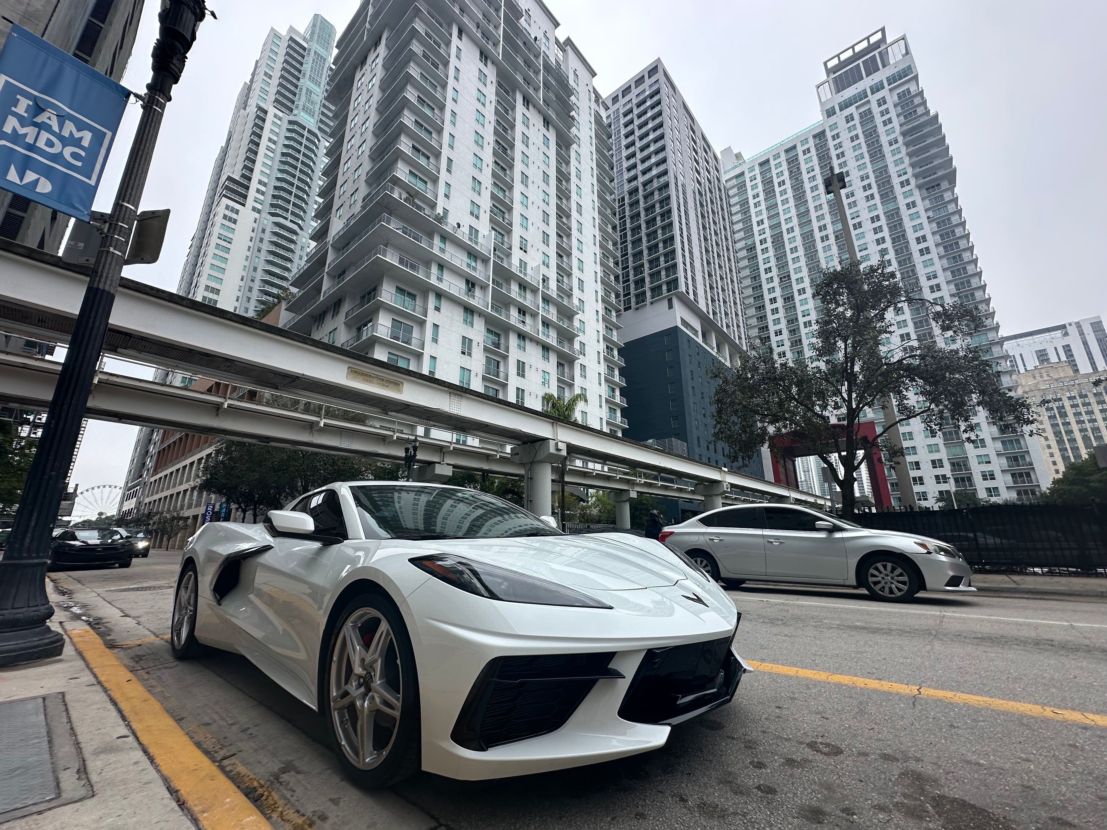 White sports car on a city street with tall buildings in the background