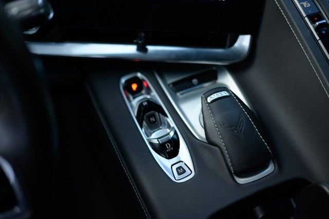 Close-up of a car's gear shift lever and surrounding controls.