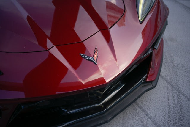 Close-up of a red car's front grille with a visible logo.