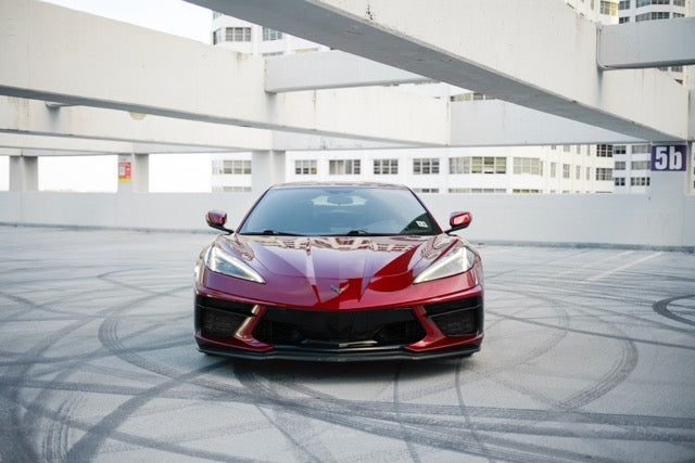 Red sports car on a rooftop with modern architecture in the background