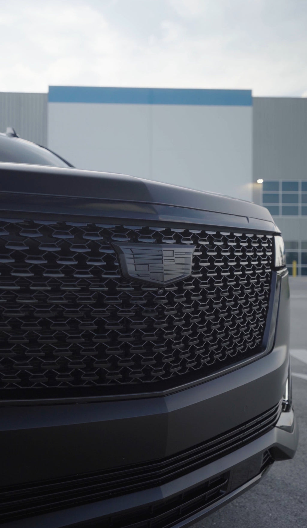 Close-up of a car's front grille with a building in the background