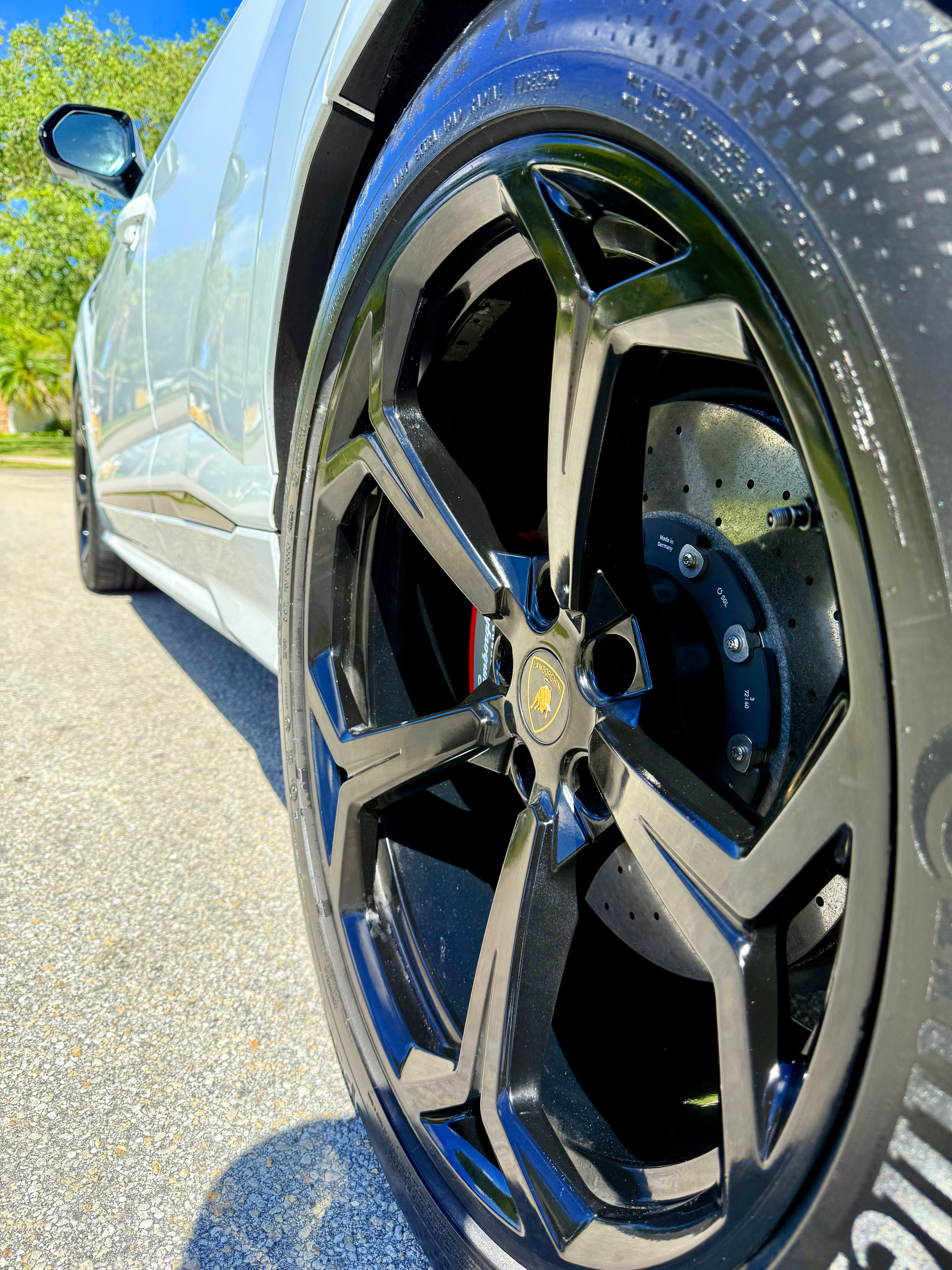 Close-up of a car wheel with a visible Lamborghini logo on a road.