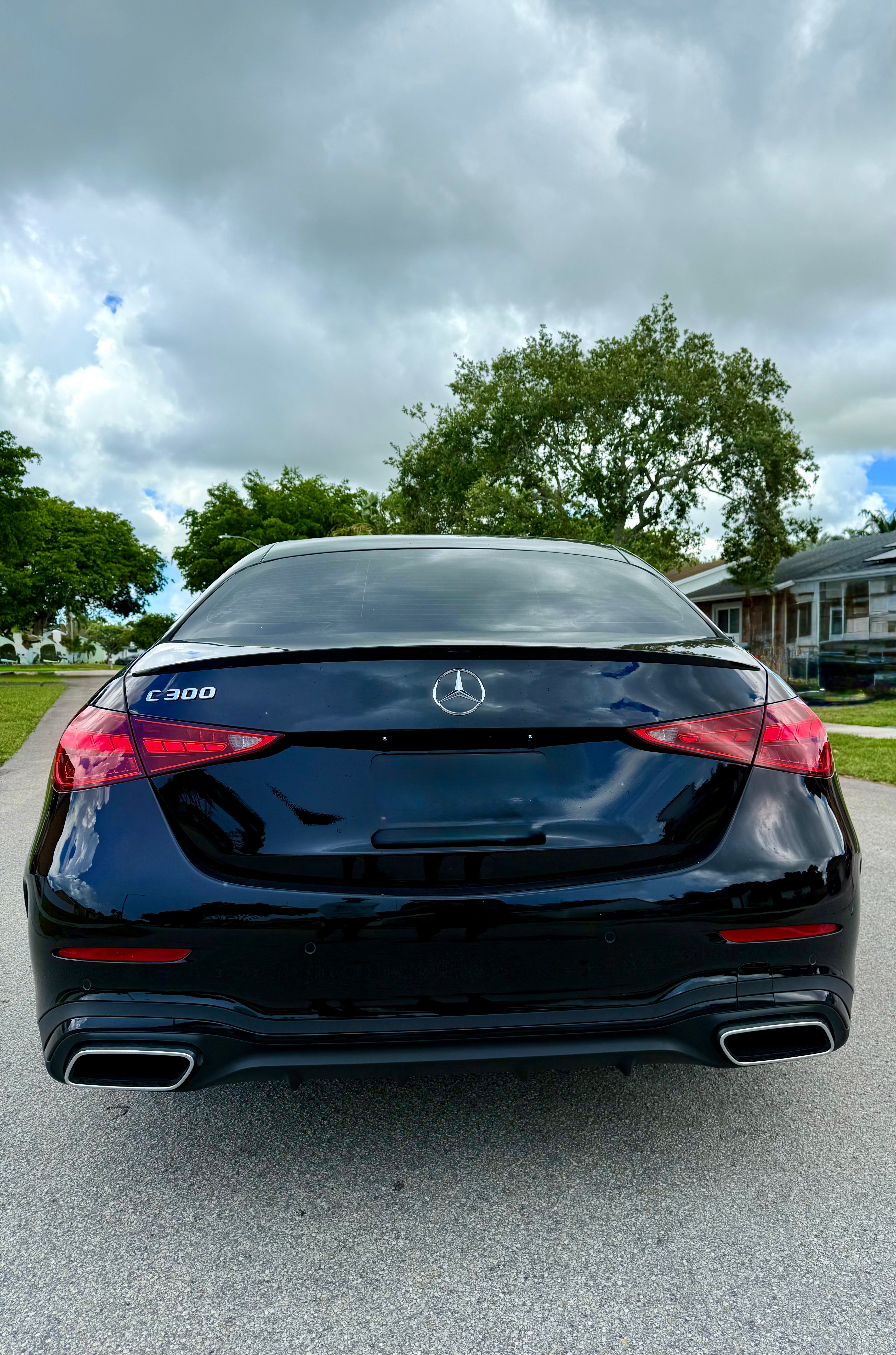 Black Mercedes-Benz car parked on a street with trees and houses in the background