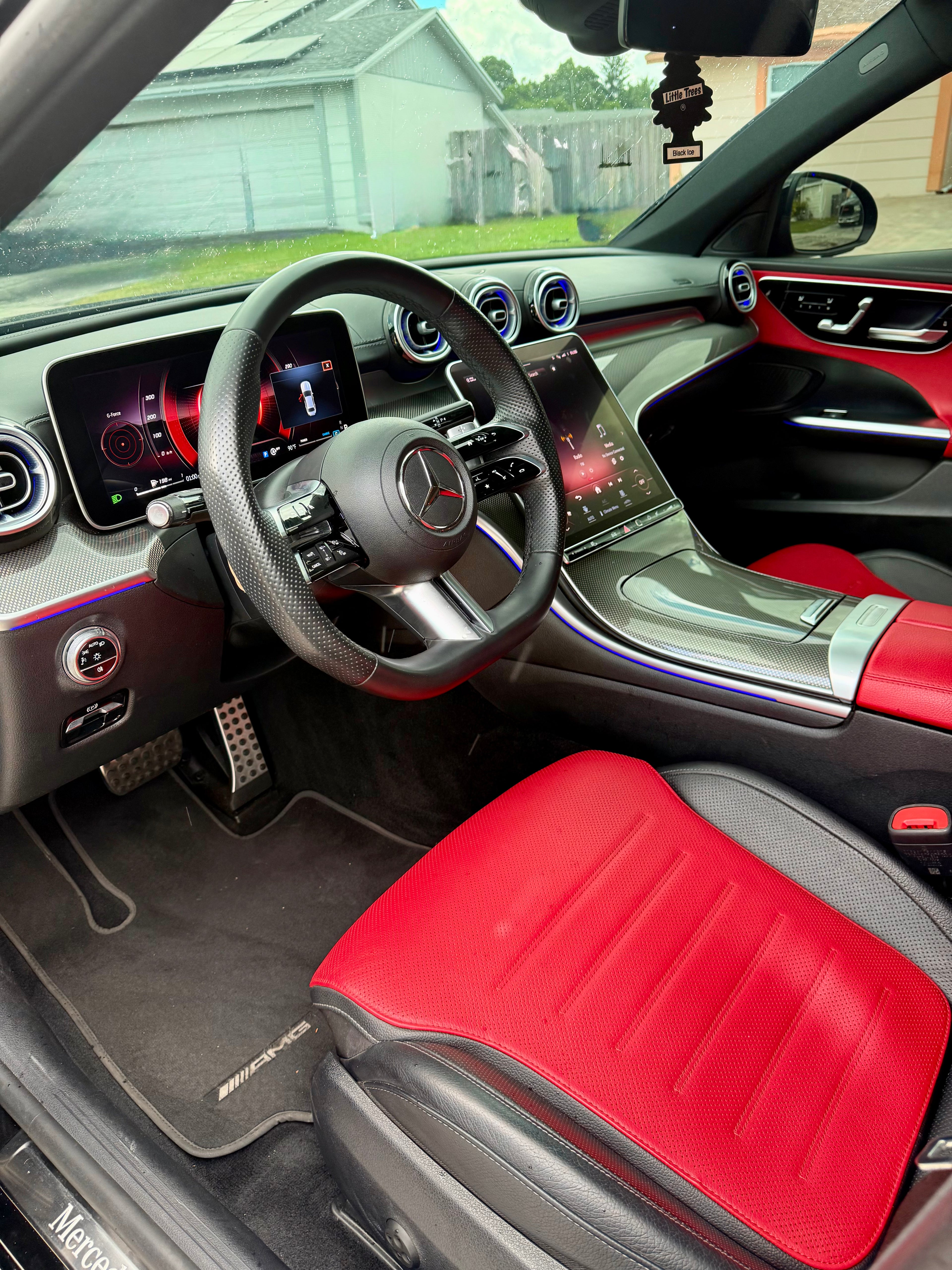 Car interior with red and black seats, dashboard, and steering wheel.