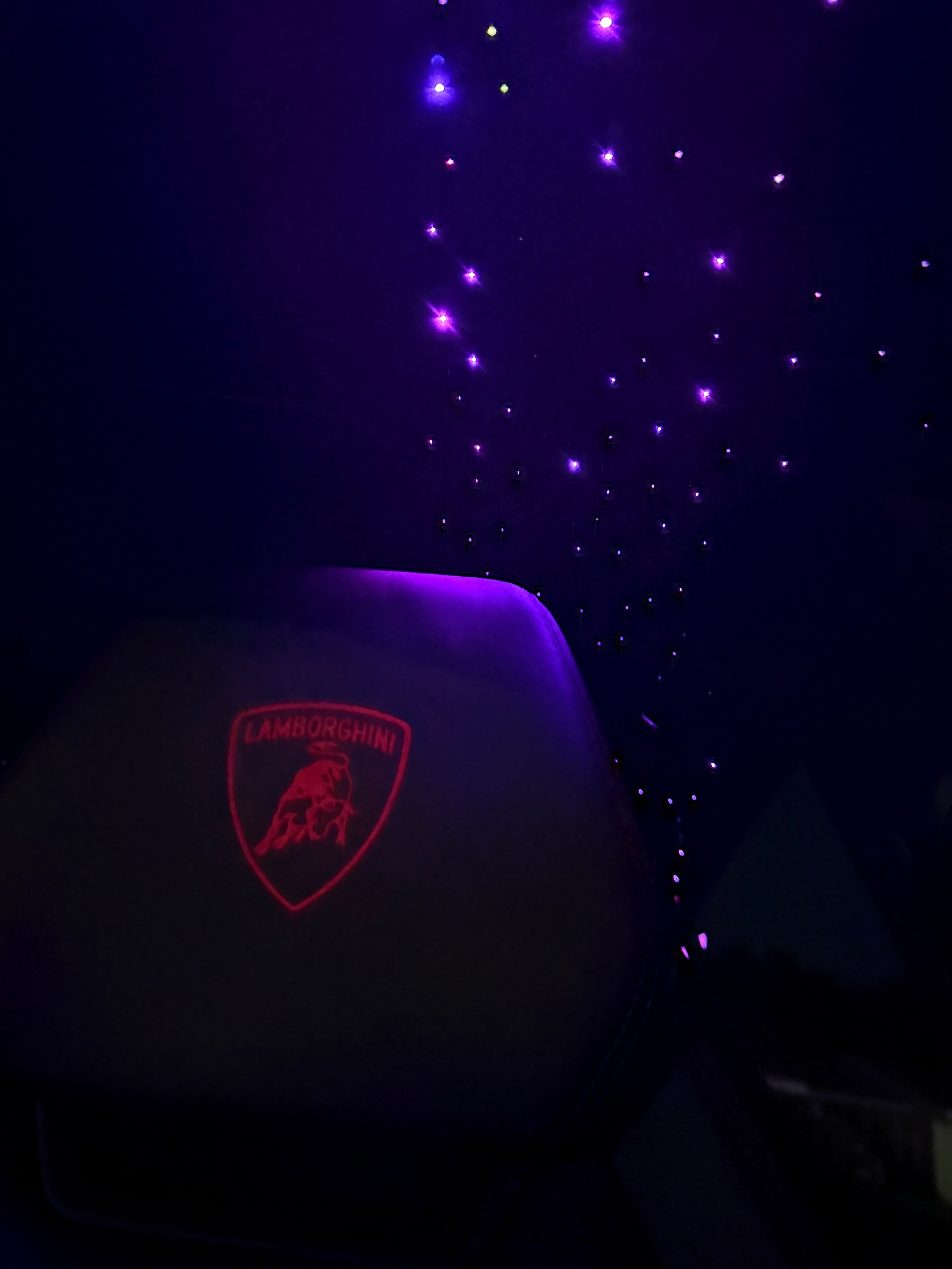 Car seat with Lamborghini logo against a starry night sky background