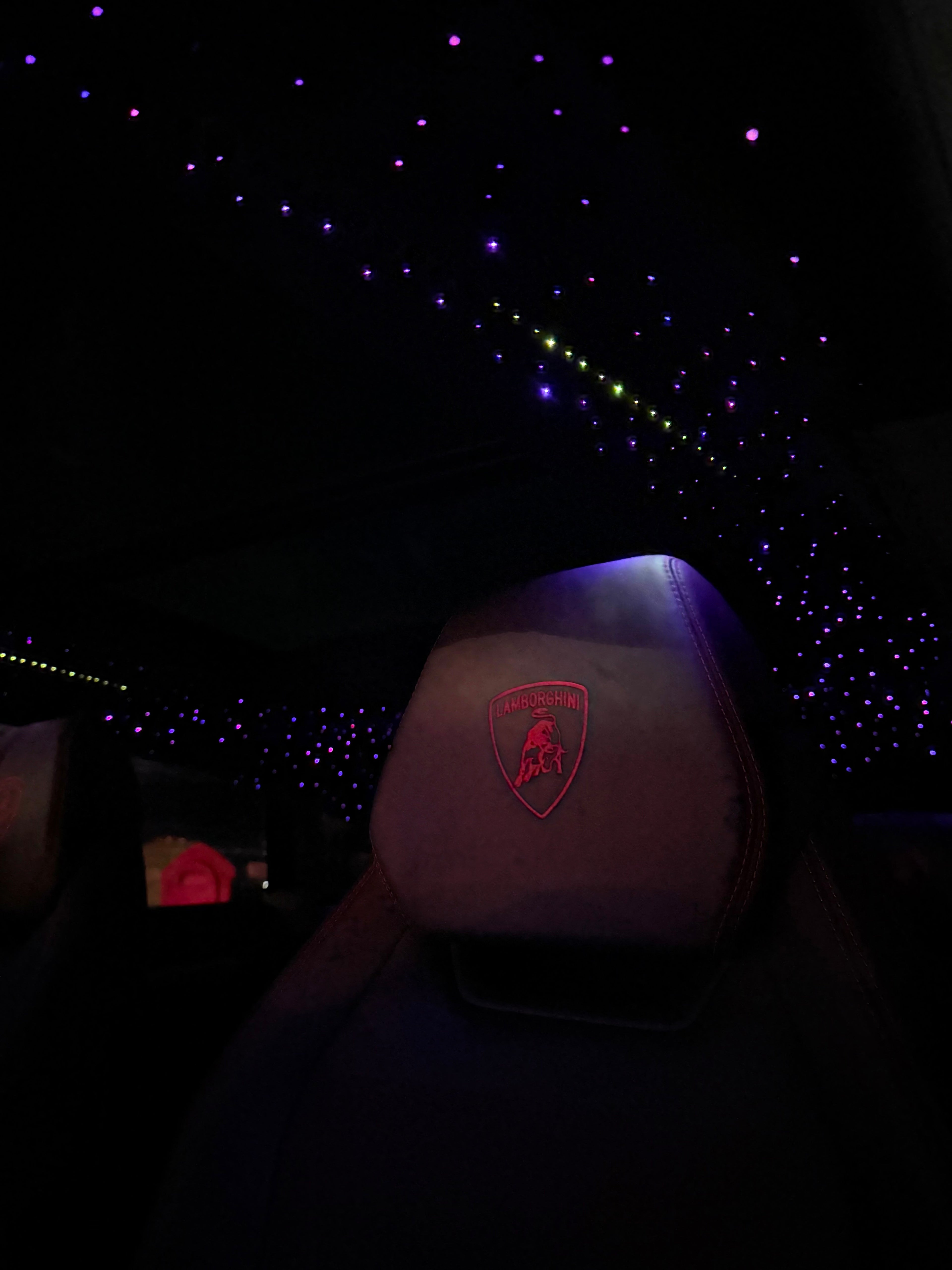 Lamborghini Urus interior with a headrest featuring a logo against a starry night sky.