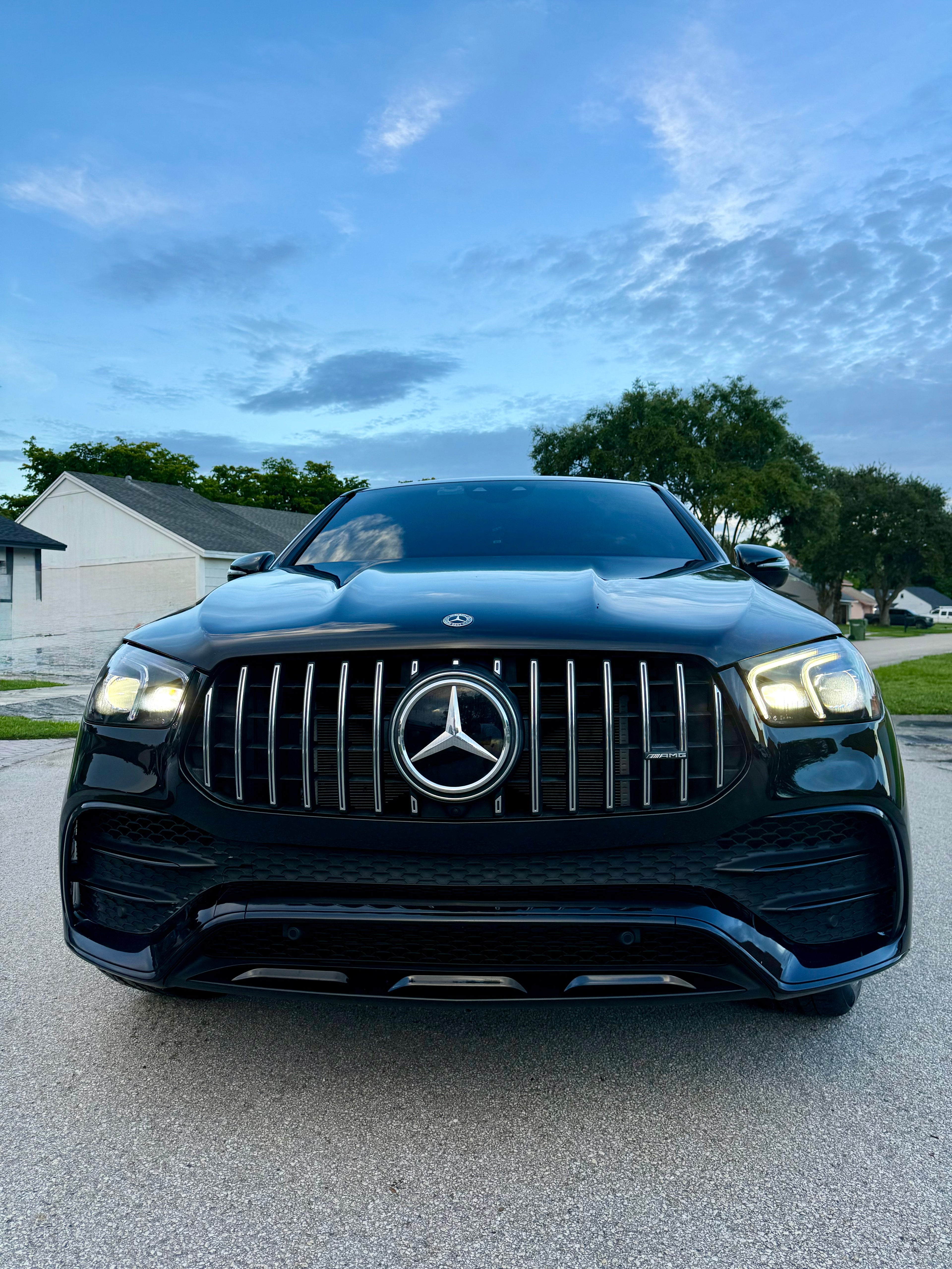 Black Mercedes-Benz car on a driveway with a clear sky background