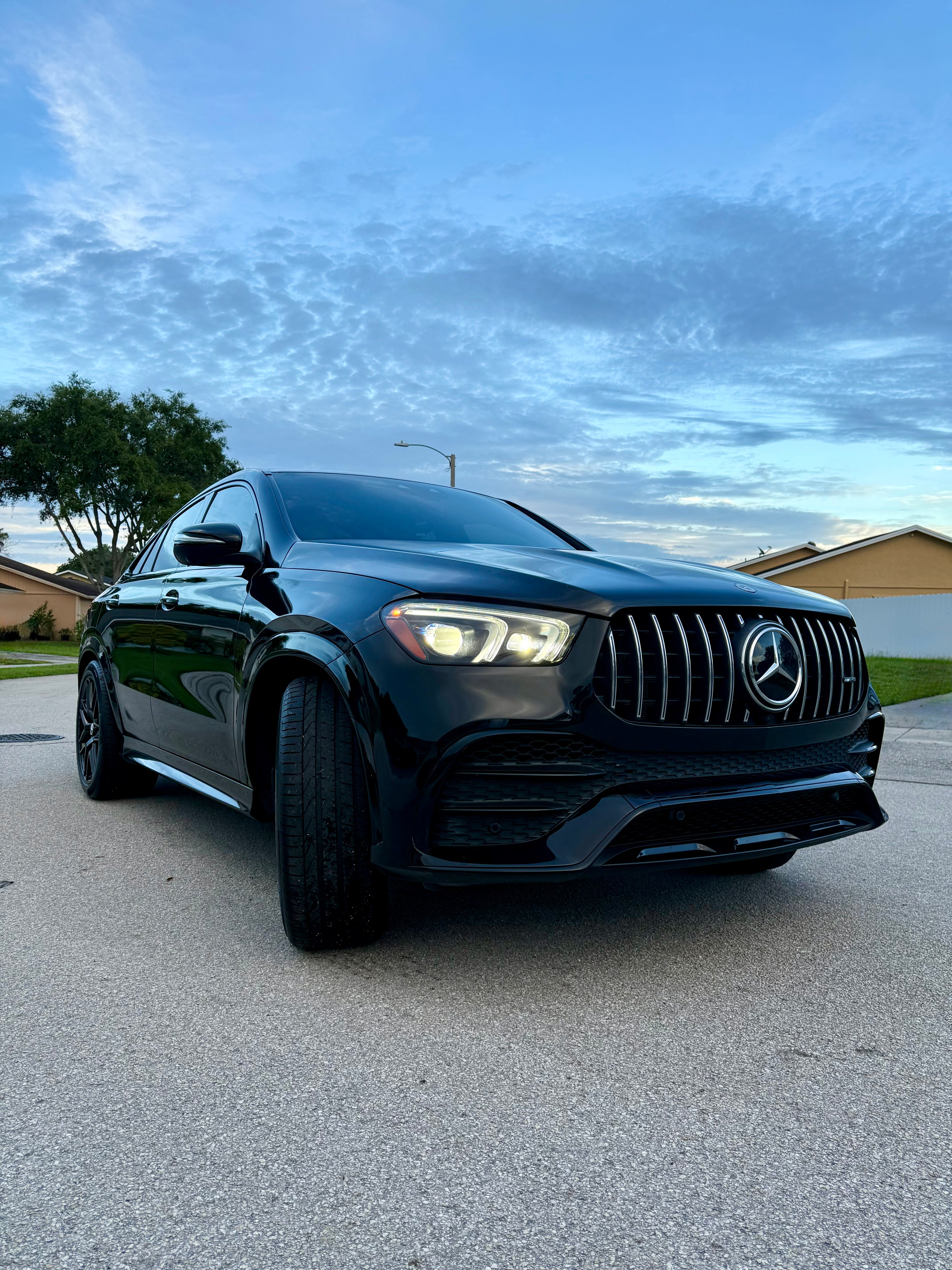 Black Mercedes-Benz car on a street with a clear sky.