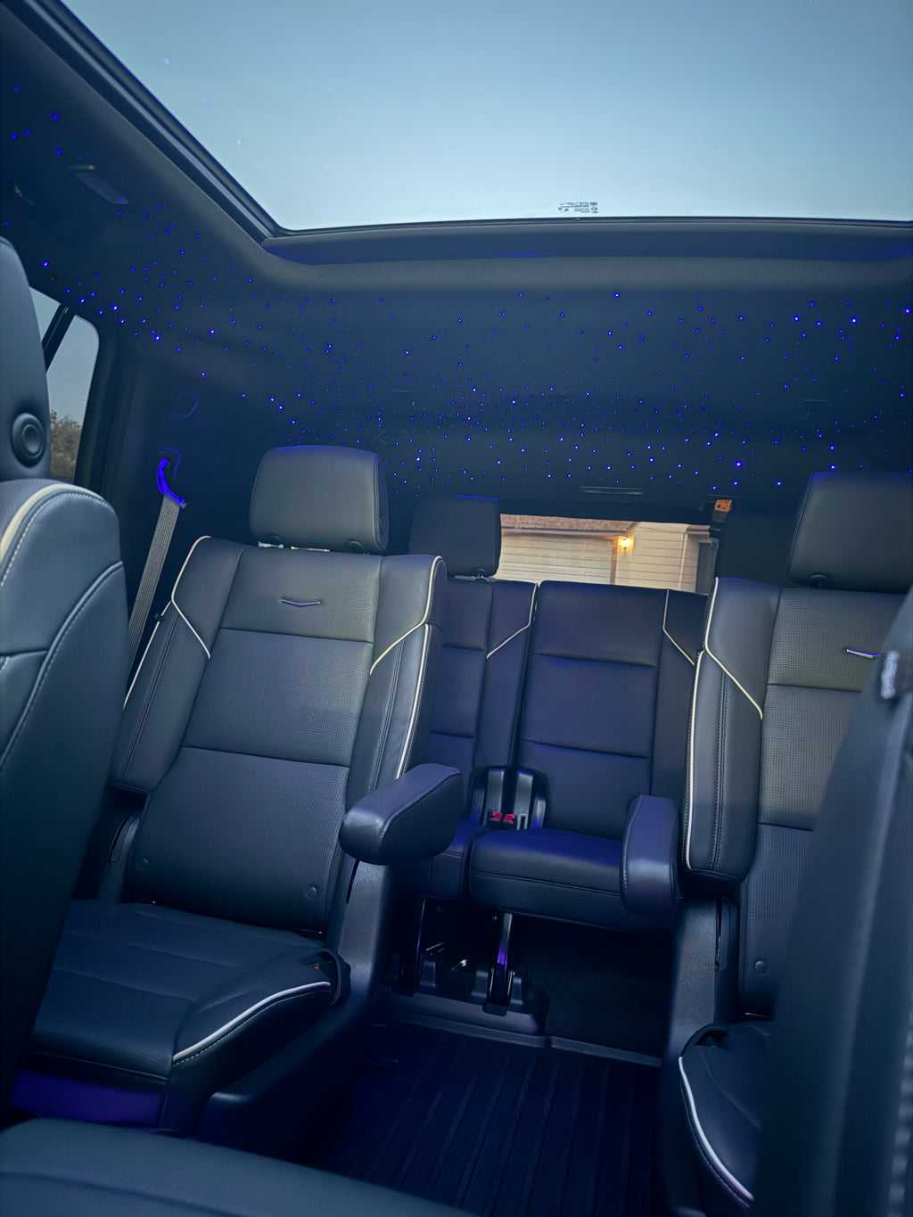 Interior of a vehicle with black seats and a starry sky ceiling effect.