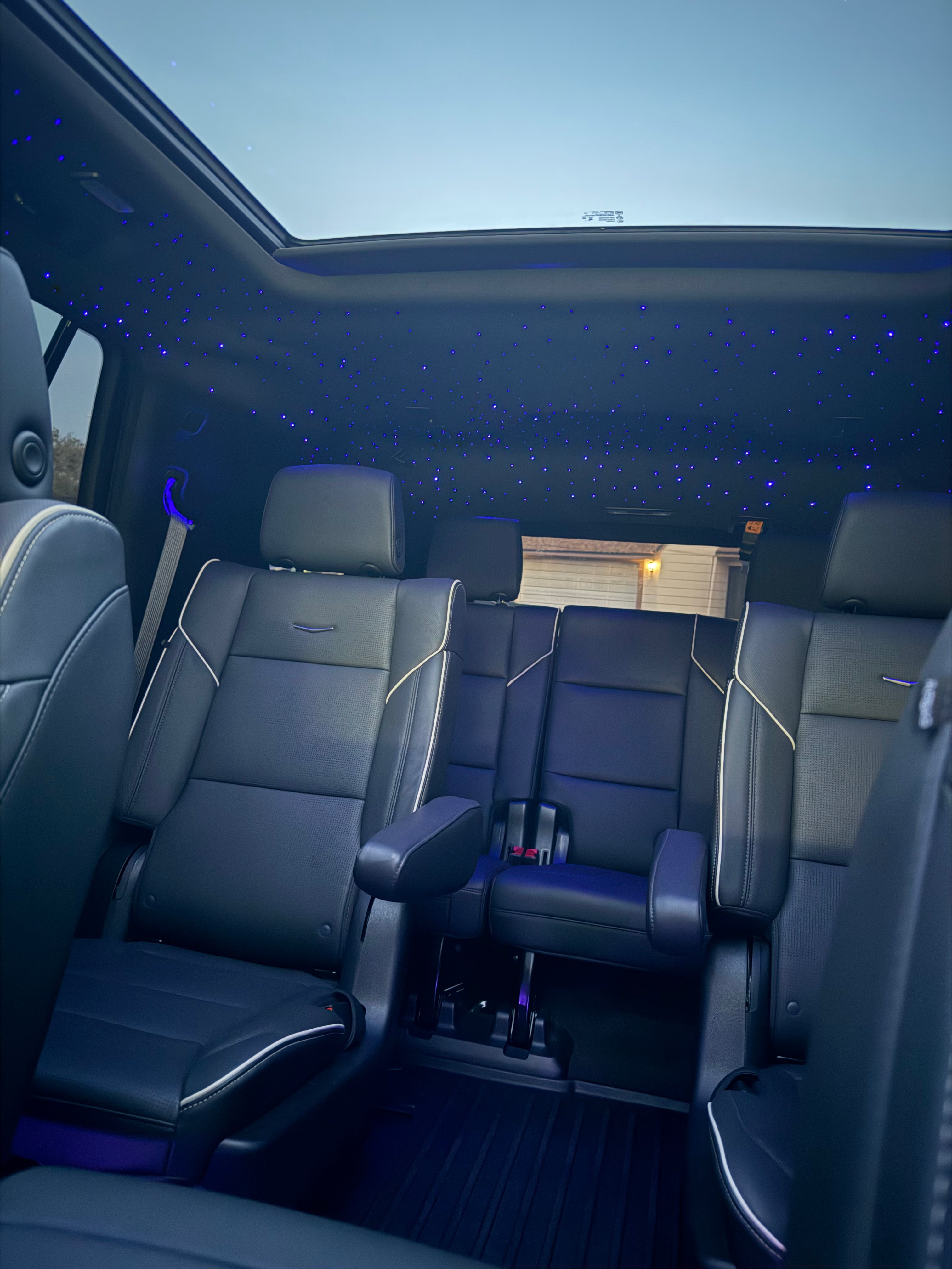 Interior of a vehicle with black seats and a starry sky ceiling effect.