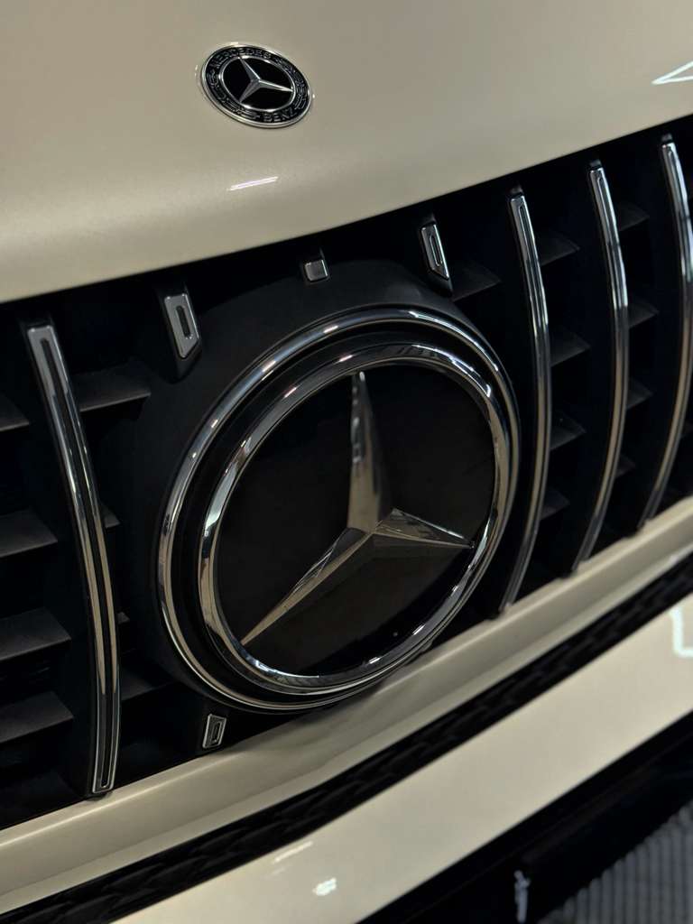 Close-up of a Mercedes-Benz emblem on a car grille.