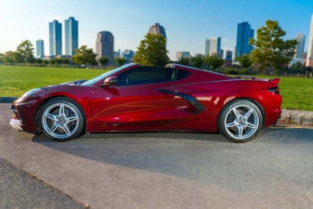 Red sports car on a road with a city skyline in the background