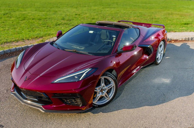 Red sports car on a road with grass in the background