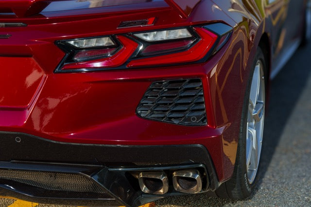 Close-up of a red car's front end with a focus on the grille and headlights.