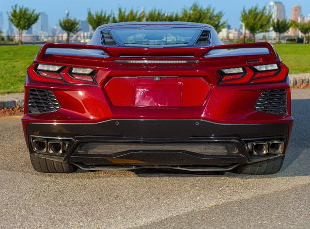 Red sports car with a black rear bumper on a city street.