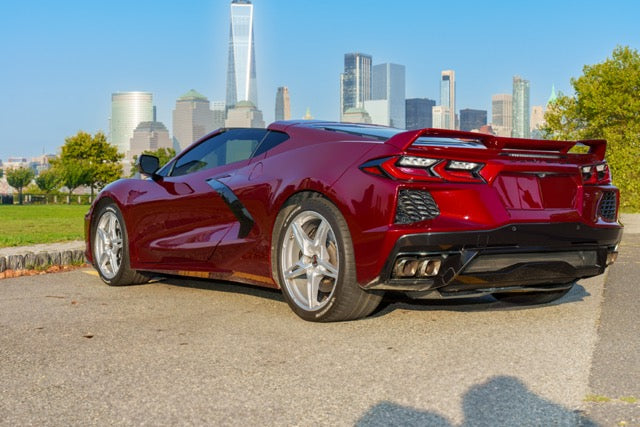 Red sports car parked on a street with a city skyline in the background