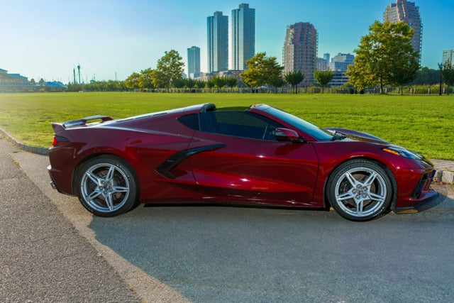 Red sports car on a road with a cityscape in the background