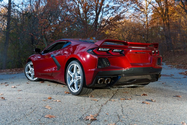 Red sports car parked on a road with trees in the background