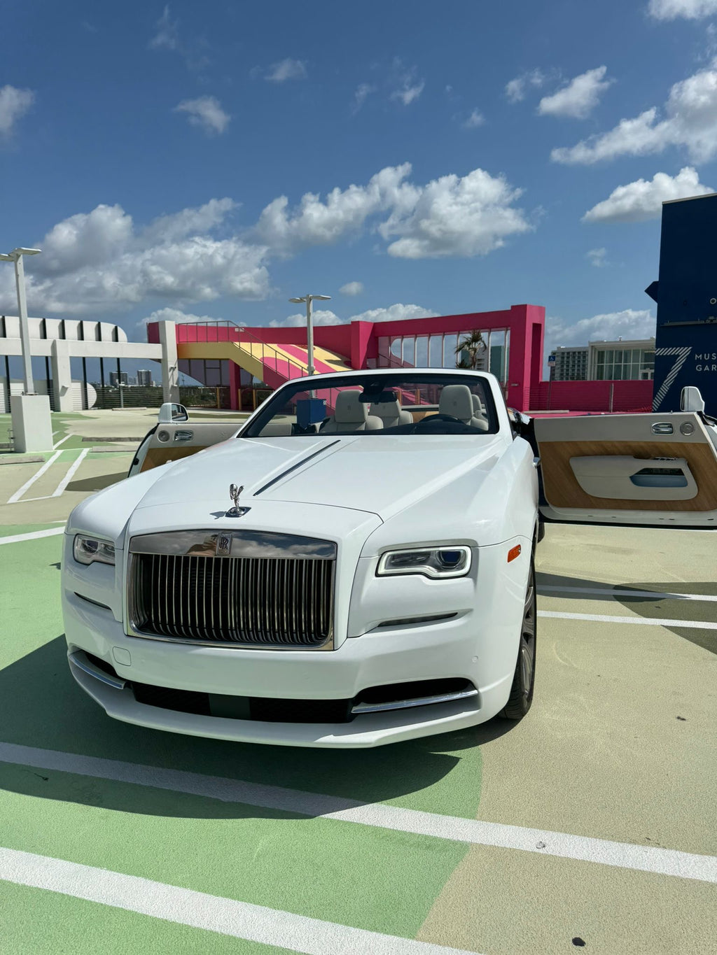 White Rolls-Royce car on a colorful pavement with a building and sky in the background