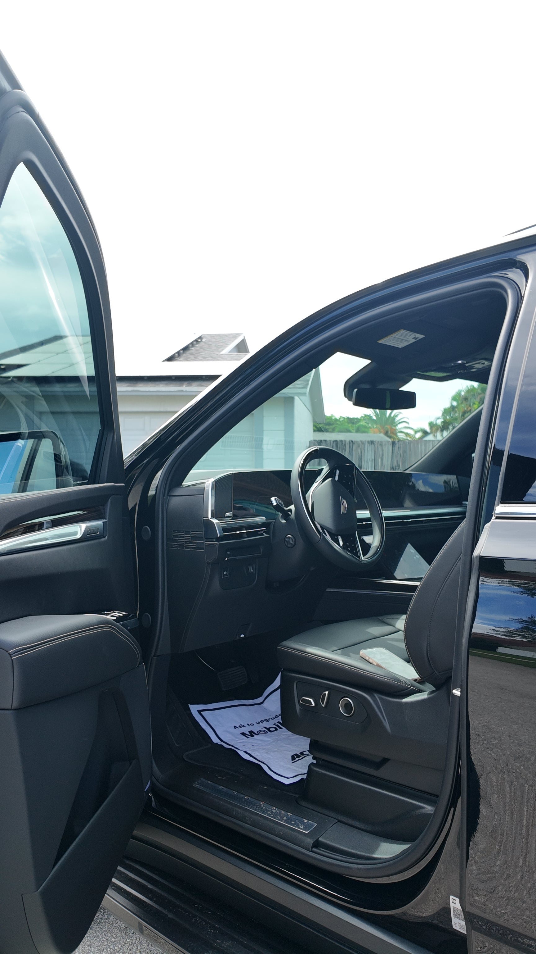 Black car interior with open door, showing dashboard and steering wheel.